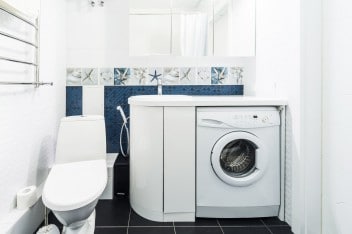 Modern bathroom with shiny white cabinets and washing machine