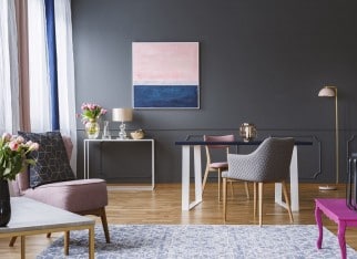 Pink and navy blue painting in grey living room interior with flowers and armchair. Real photo