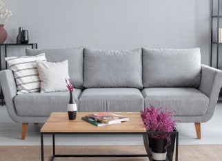 Real photo of a grey sofa, coffee table and lavender flower in a living room interior