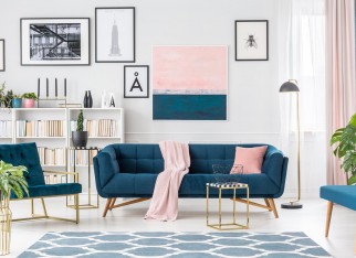 Gold table in front of a navy blue couch with pink blanket in elegant living room interior with painting