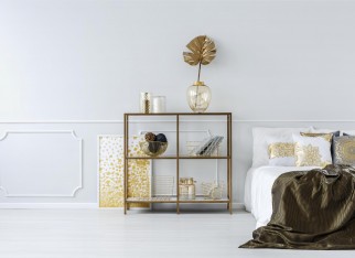 Gold leaf in vase on a shelf against white molding wall in sophisticated bedroom interior with bed