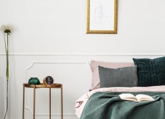 Golden, metal bedside table with clock standing in elegant female bedroom interior