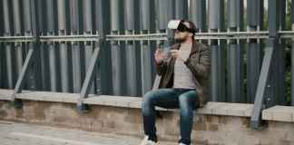 bearded attractive man uses virtual reality glasses on the roof, takes off his glasses and walks away